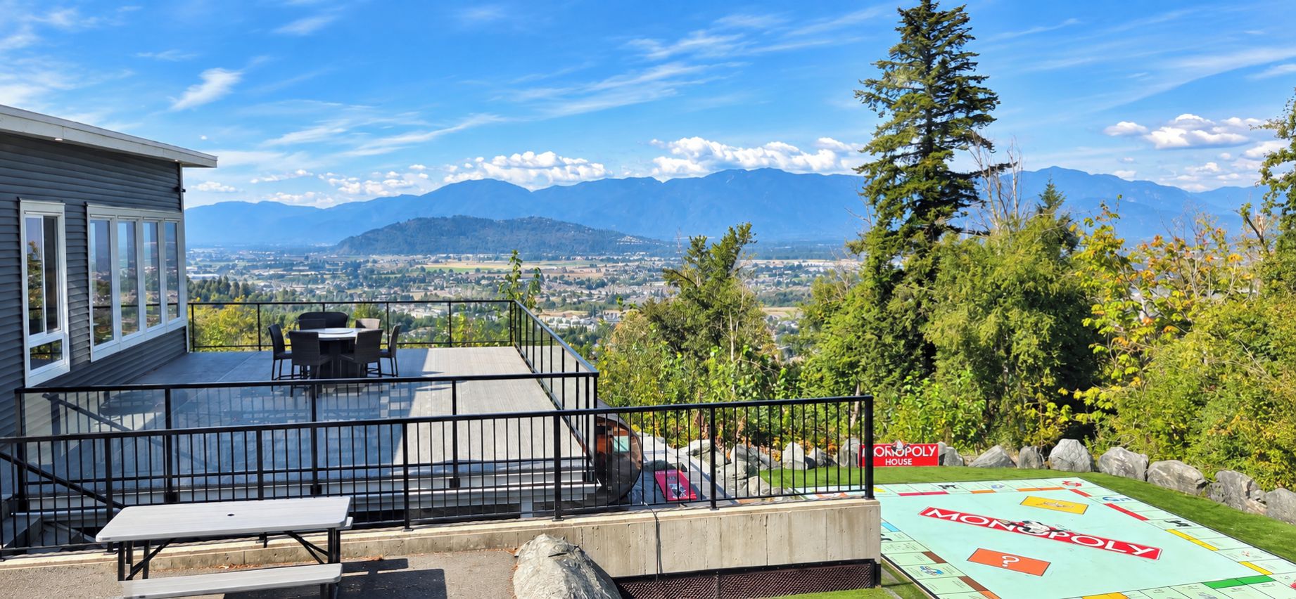 A balcony with a view of mountains, a Monopoly board game, and outdoor furniture.