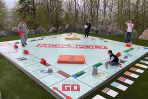 A large outdoor board game setup with Monopoly pieces and players.