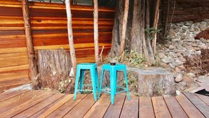 Una terraza de madera con dos taburetes turquesa y una pared rústica de piedra.