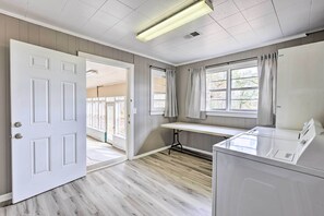 A laundry room with a white door, a window with curtains, and a table.