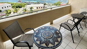 A balcony with a tiled floor, a round table with a mosaic top, and four chairs. - Spacious 1Bed 1Bath Condo In Downtown Red Hook (East End)