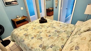 A bedroom with a bed, a bedside table, a mirror, and a window. - Spacious 1Bed 1Bath Condo In Downtown Red Hook (East End)