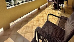 A covered outdoor seating area with a view of a marina and distant hills. - Harbor View: 2Bed 1Bath Loft In Downtown Red Hook! (East End)