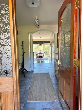 A hallway with a wooden door, a rug, and a dining area in the background. - Amazing Mountain Views, Hot Tub and Close to Wineries and Breweries (Afton)