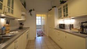Eine Küche mit weißen Schränken, gefliestem Boden, einer Kaffeemaschine und einem Toaster.