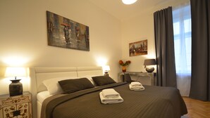 Ein ordentlich bezogenes Bett mit brauner Bettdecke und Kissen, ein Nachttisch mit Lampe sowie ein Bild an der Wand.
