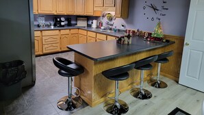 Una cocina con armarios de madera, un refrigerador negro, una cafetera y un reloj en la pared.