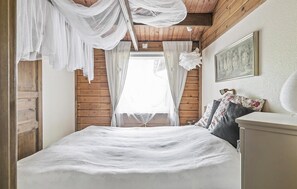 Een slaapkamer met een groot bed, houten wanden en een hemelbed.