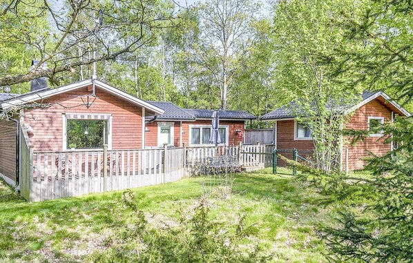 Een rij houten hutten met een houten terras en een omheind erf.