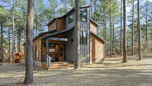 A modern log cabin with a wooden exterior, large windows, and a welcoming entrance. - Family & Group Cabin w/ Hot Tub & Game Room (Broken Bow)