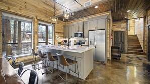 A spacious kitchen with a large island, stainless steel appliances, and a view of the outdoors. - Family & Group Cabin w/ Hot Tub & Game Room (Broken Bow)