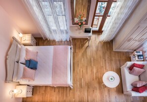 A bedroom with a bed, bedside table, lamp, and a small round table with a vase of flowers.