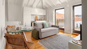 Eine moderne Küche mit weißen Schränken, einem grauen Sofa und einem Esstisch mit Stühlen.