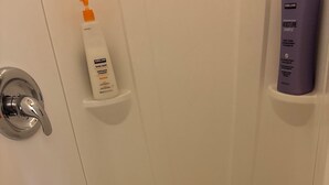 Kylpyhuoneessa on valkoinen pesuallas, peili ja hyllyjä, joilla on hygieniatuotteita.