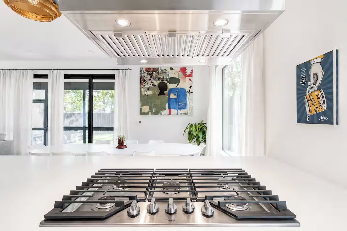 A modern kitchen with a central island, stainless steel appliances, and a large window with curtains.