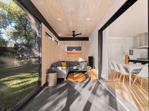 Un interior moderno con techo de madera, un sofá gris, una mesa de comedor con sillas y una zona de cocina.