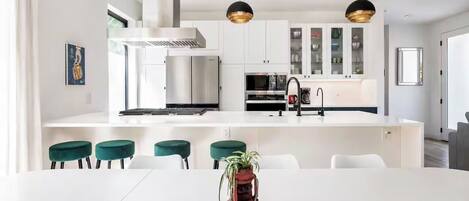 A modern kitchen with white cabinets, stainless steel appliances, and a central island with bar stools.