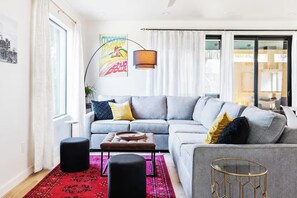 A modern living room with a grey sofa, a round coffee table, and a red patterned rug.
