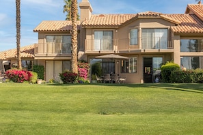 A two-story house with a patio, large windows, and a well-maintained lawn.