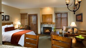 Quarto de hotel com cama, lareira, mesa de jantar com cadeiras e sala de estar com sofá.