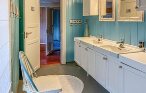Bathroom features a double sink, mirror, and chair.