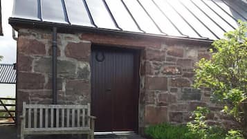 A stone building with a dark wooden door and a metal roof.