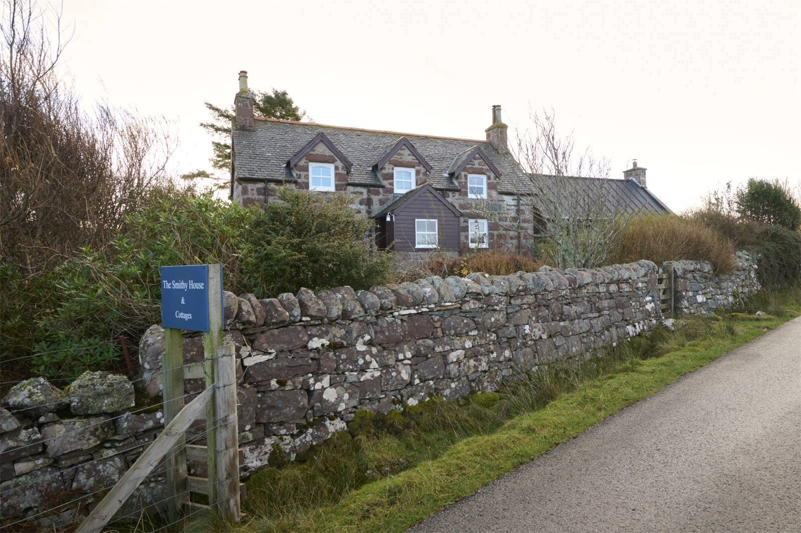 Mur de pedra amb un cartell de The Smithy House & Cottages.