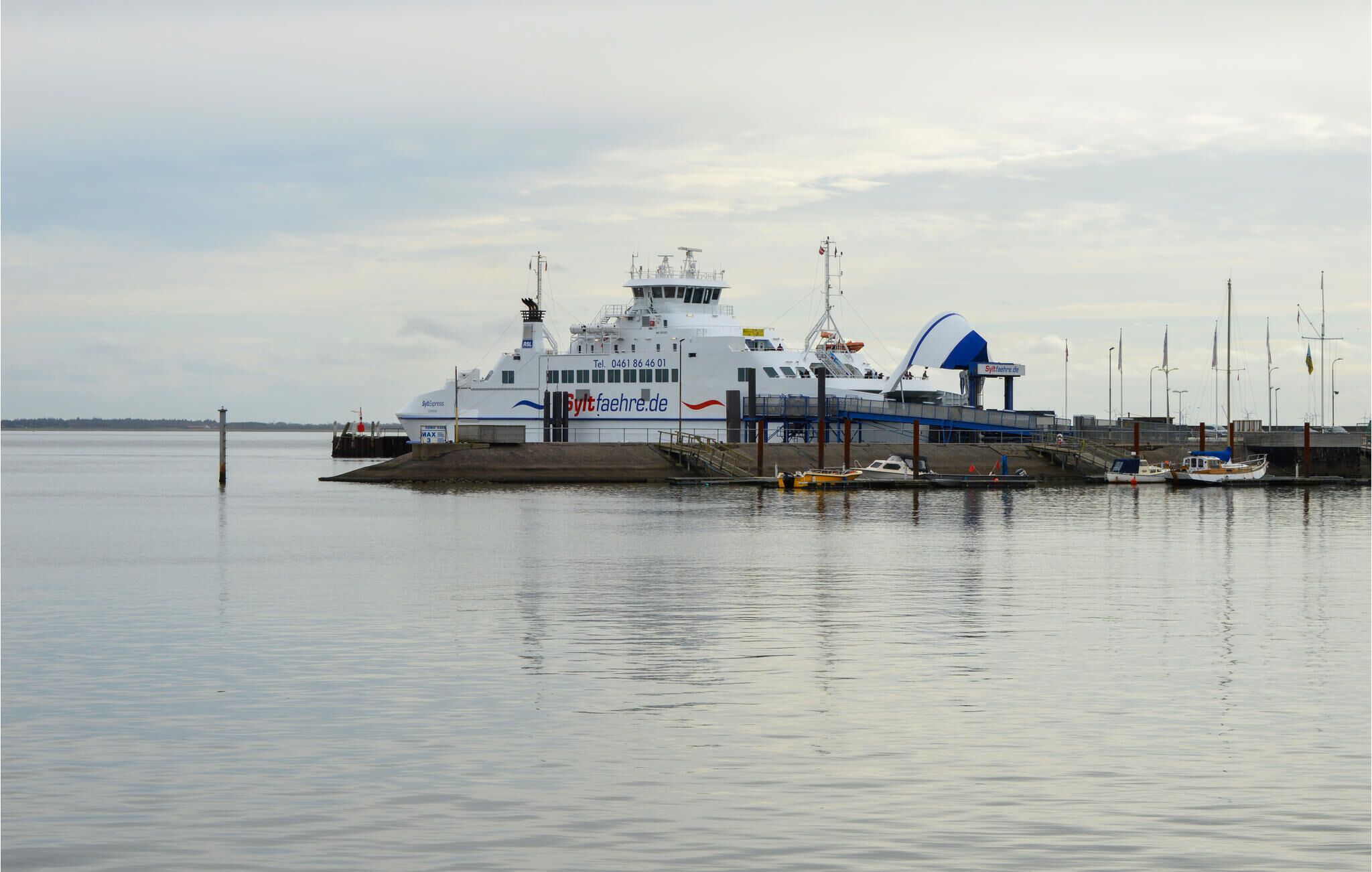 Un ferry était amarré à un quai, avec une étendue d’eau calme en arrière-plan.