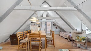 A cozy attic bedroom with a wooden dining table, chairs, a hanging chair, and a bed with a colorful bedspread. - 3 bedroom stunning home in Rømø (Rømø)