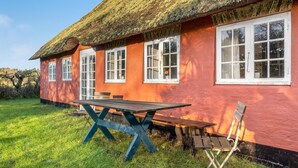 A house with a thatched roof, a red exterior, and a wooden table and chairs in the yard. - 3 bedroom stunning home in Rømø (Rømø)