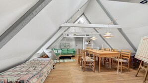 A cozy attic room with a wooden dining table, chairs, a green sofa, and a patterned bedspread. - 3 bedroom stunning home in Rømø (Rømø)