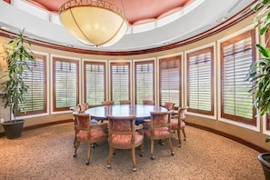 Conference room with a round table and six chairs, featuring a large ceiling light and large windows.