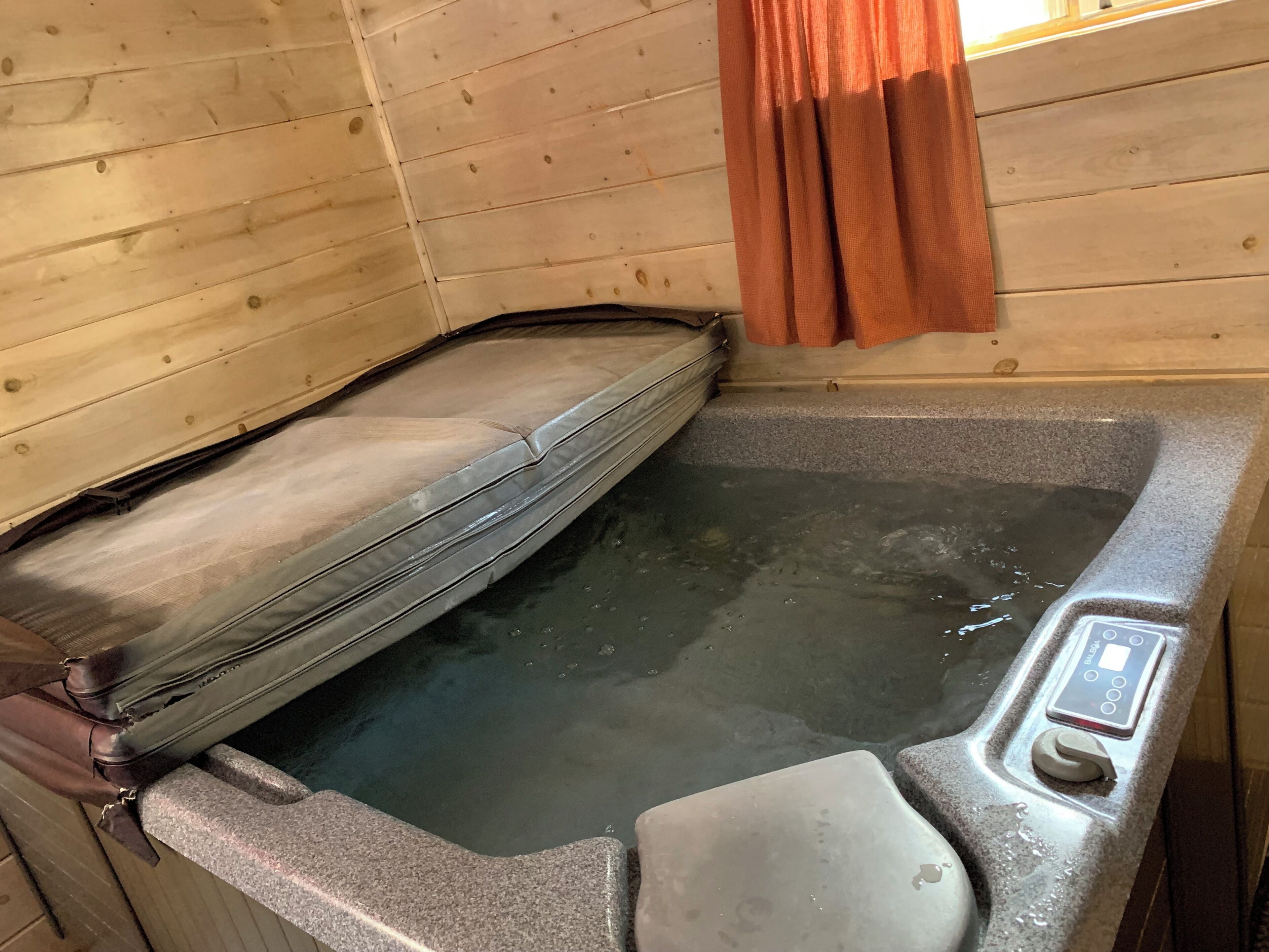 Eine Holzhütte mit Whirlpool, Holzwänden und Bedienfeld.