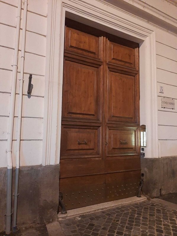 A large wooden double door with a sign above it reading "CONDOMINIO". - Quintus Luxury Suites (Rome)