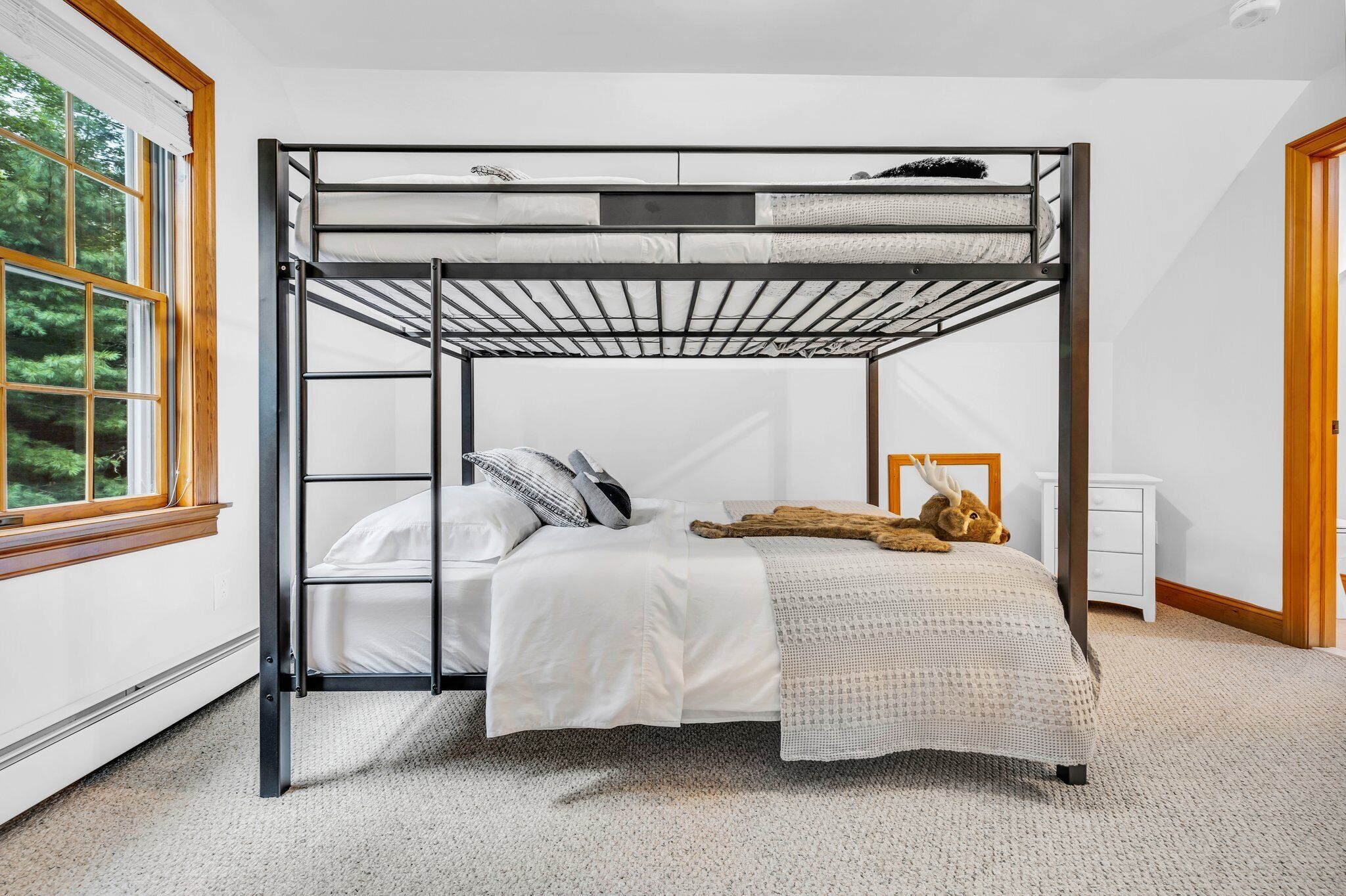 Een stapelbed met wit beddengoed en een houten hoofdbord.