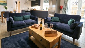 A modern living room with two dark sofas, a wooden coffee table, and a kitchen in the background. - Bracken Cottage (York)