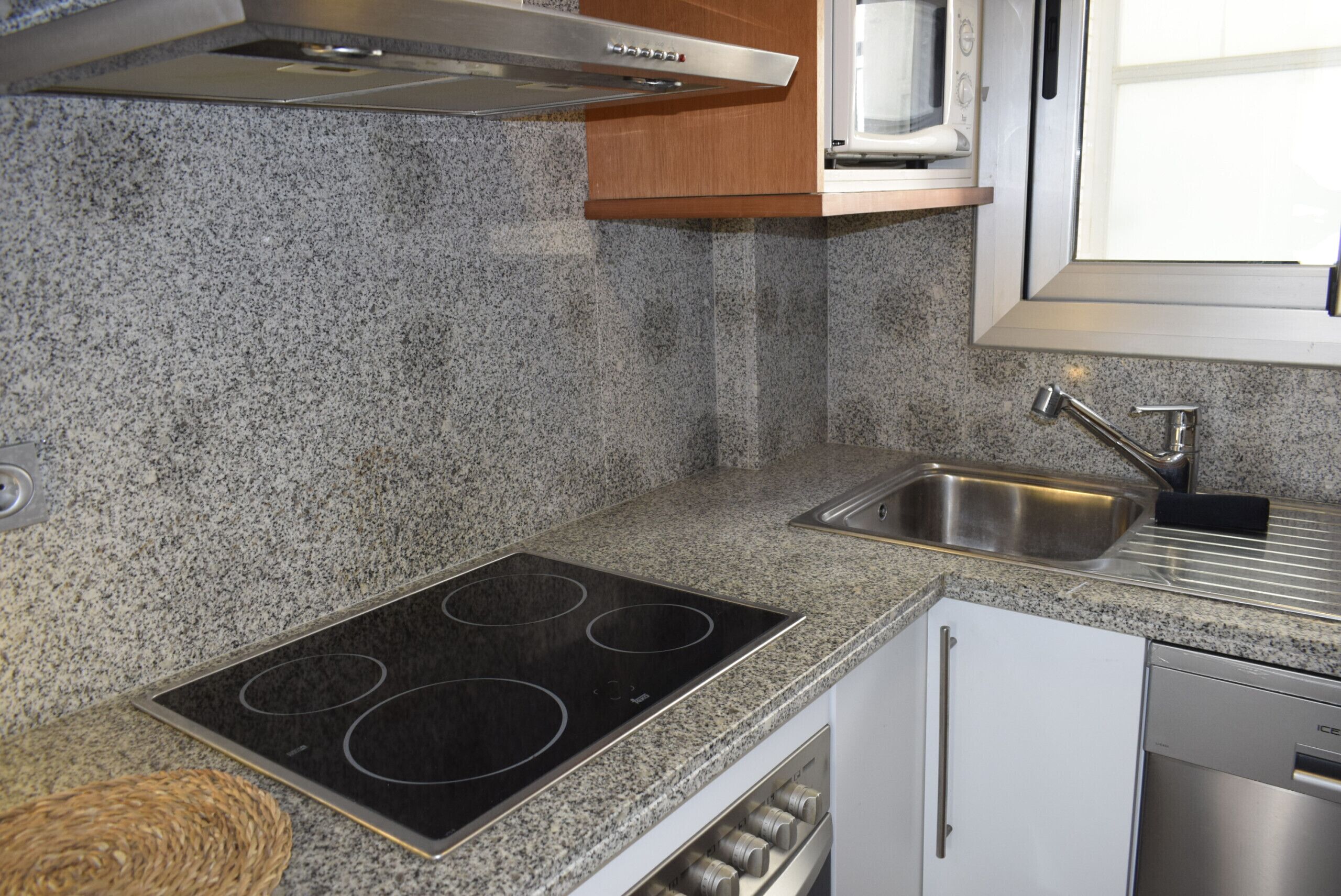 A kitchen with granite countertops, a stainless steel sink, a built-in microwave, and a stove.