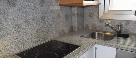 A kitchen with granite countertops, a stainless steel sink, a built-in microwave, and a stove.