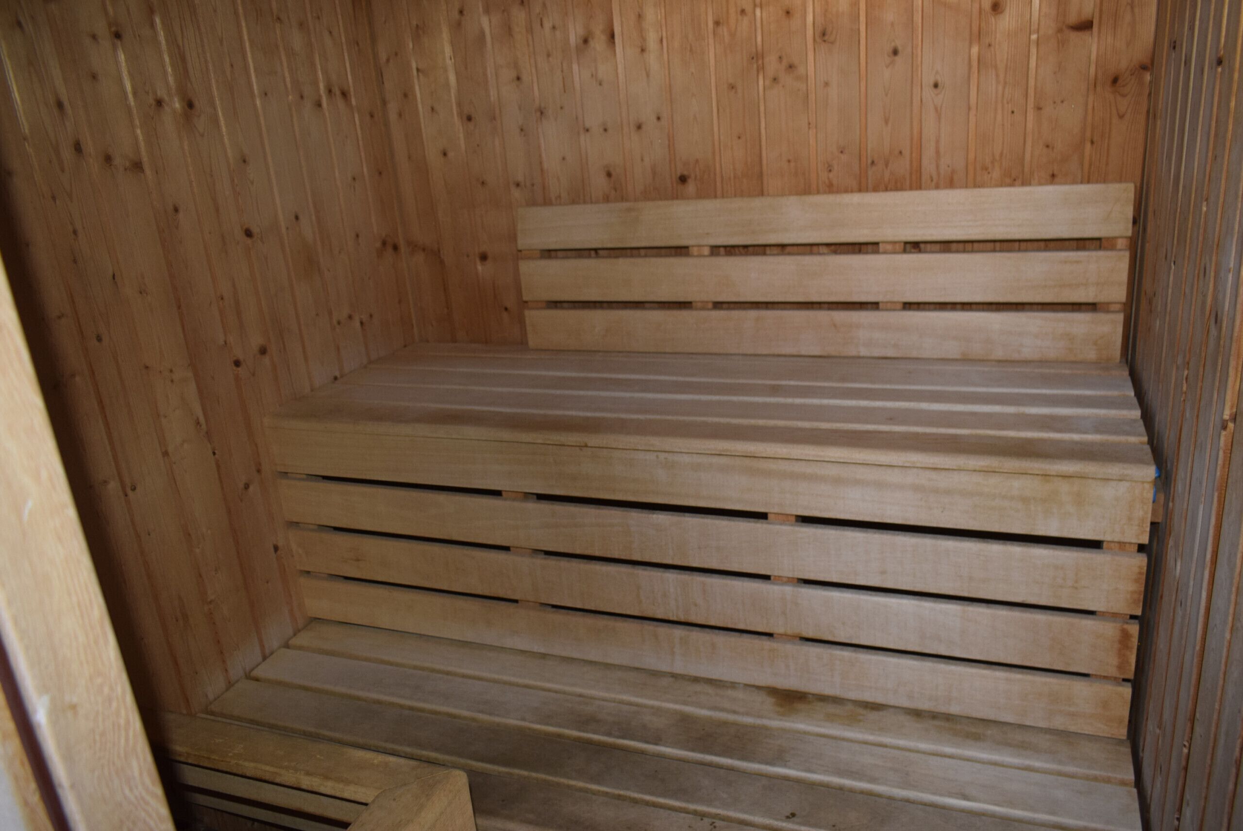 Un sauna en bois, doté de bancs et d’un plancher incliné.