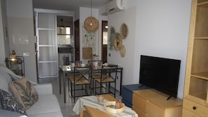 Un salon moderne comprenant un canapé, un téléviseur, un meuble en bois et un coin repas avec des chaises et une table.
