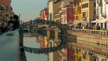 Ein Kanal mit einer Brücke, Gebäude spiegeln sich im Wasser, und Menschen sind zu sehen.