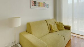 A living room with a sofa, a lamp, and a framed artwork on the wall. - 50m2 Apartment Near Milano Centrale (Milan)