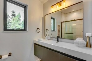 Un bagno moderno con uno specchio grande, una finestra e un piano d'appoggio bianco.