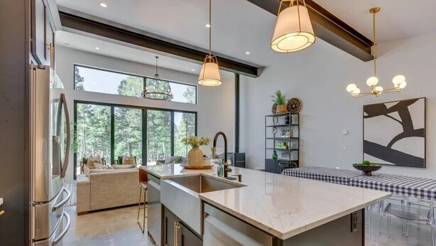 Una cocina moderna con una isla grande, iluminación colgante y vistas al exterior.