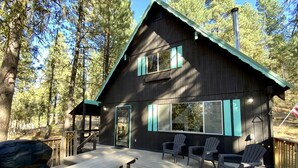 A cabin with a deck, outdoor seating, and a covered picnic table. - Mint Chip Cabin - Pet friendly - Forested - Large deck - Fire pit (Cascade)