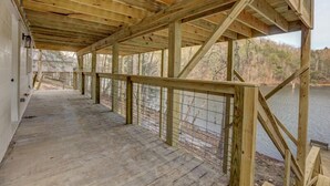 A wooden deck with a railing overlooking a body of water, supported by wooden beams and columns. - Lakefront Home w/ Dock · King Suite · Stunning Paradise · Voted Best of Kentucky (Laurel County)