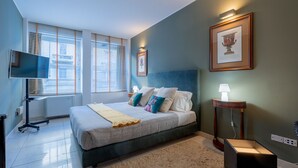 A bedroom with a bed, bedside table, lamp, and a framed picture on the wall. - The King Of Milan (Milan)