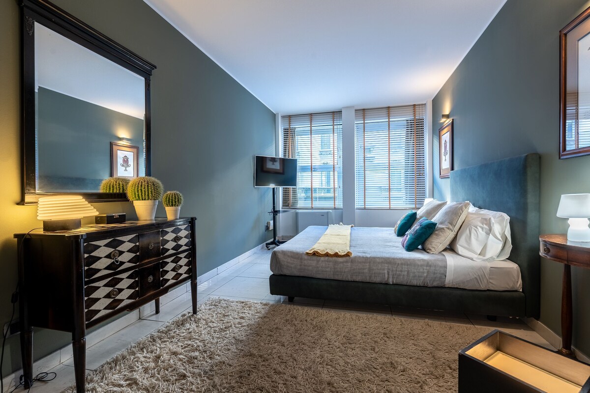 A bedroom with a bed, a dresser, a mirror, and a TV.