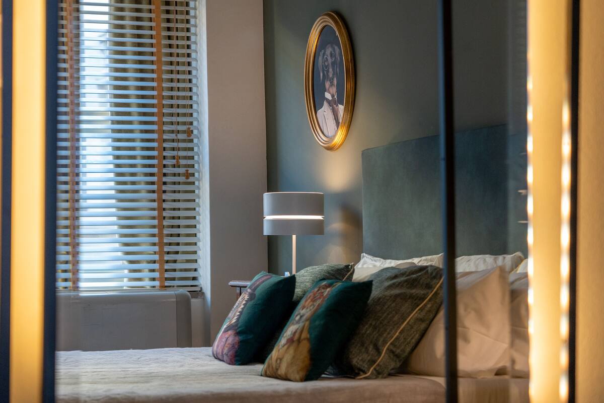 A neatly made bed with pillows, a bedside lamp, and a framed picture on the wall.