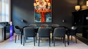 A modern dining area with a black wall, a chandelier, and a colorful abstract painting. - The King Of Milan (Milan)